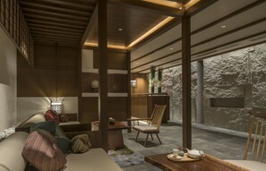 A modern interior with a wooden ceiling, a stone wall, and a seating area with cushions and a table.