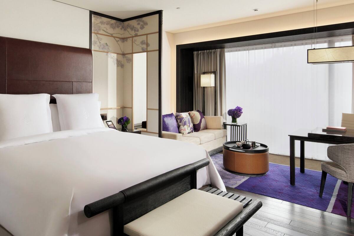 Ein Hotelzimmer mit einem großen Bett, einer Couch, einem kleinen Tisch und einem Sessel.
