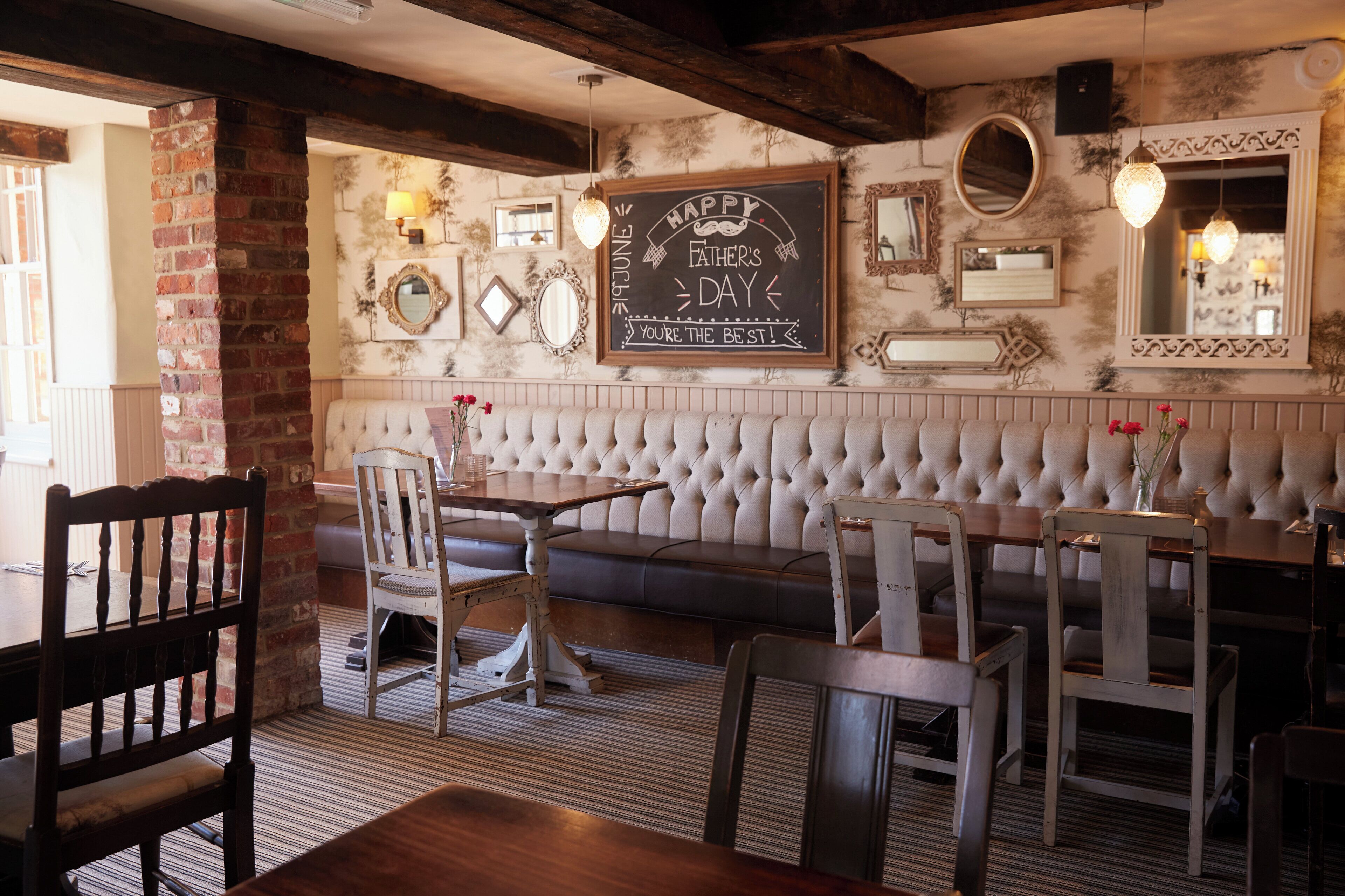 A cozy restaurant interior with a wooden table, cushioned bench seating, and a chalkboard sign on the wall.