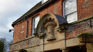 A red brick building with a stone archway and hanging flower baskets. - Wheatsheaf Hotel by Chef and Brewer Collection (Basingstoke)