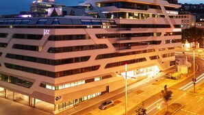 A modern multi-story building with a unique architectural design, featuring balconies and a parking structure below. - Jaz in the City Stuttgart (Stuttgart)