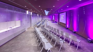 Ein Konferenzraum mit Reihen von Stühlen und einer Projektionsleinwand, auf der 'jaz stuttgart' angezeigt wird.