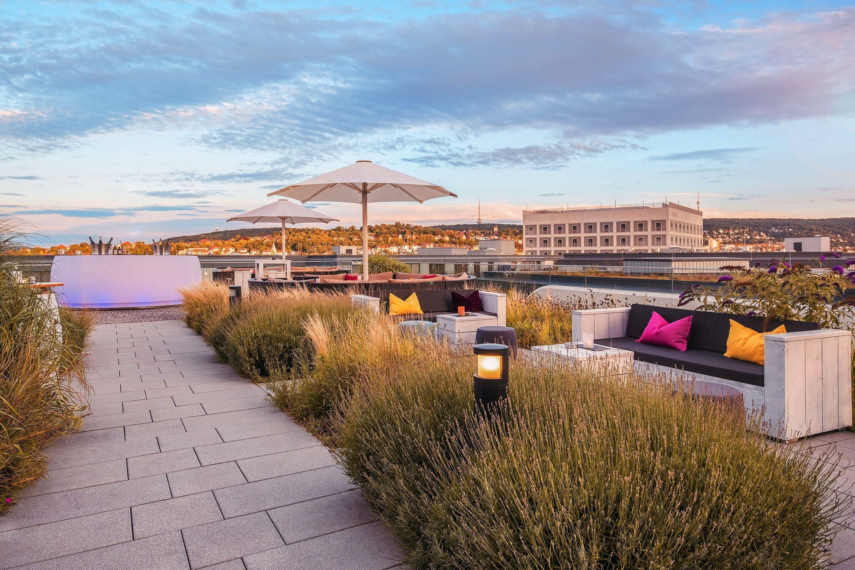 A rooftop terrace with a pathway, outdoor seating, and a view of a cityscape.