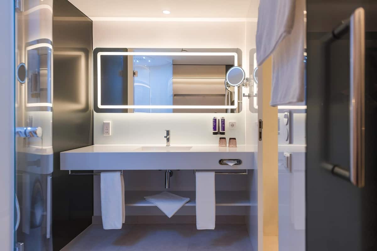 A modern bathroom with a large mirror, vanity, and a towel rack.