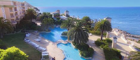 Un resort con piscina, palmeras y vista al océano.