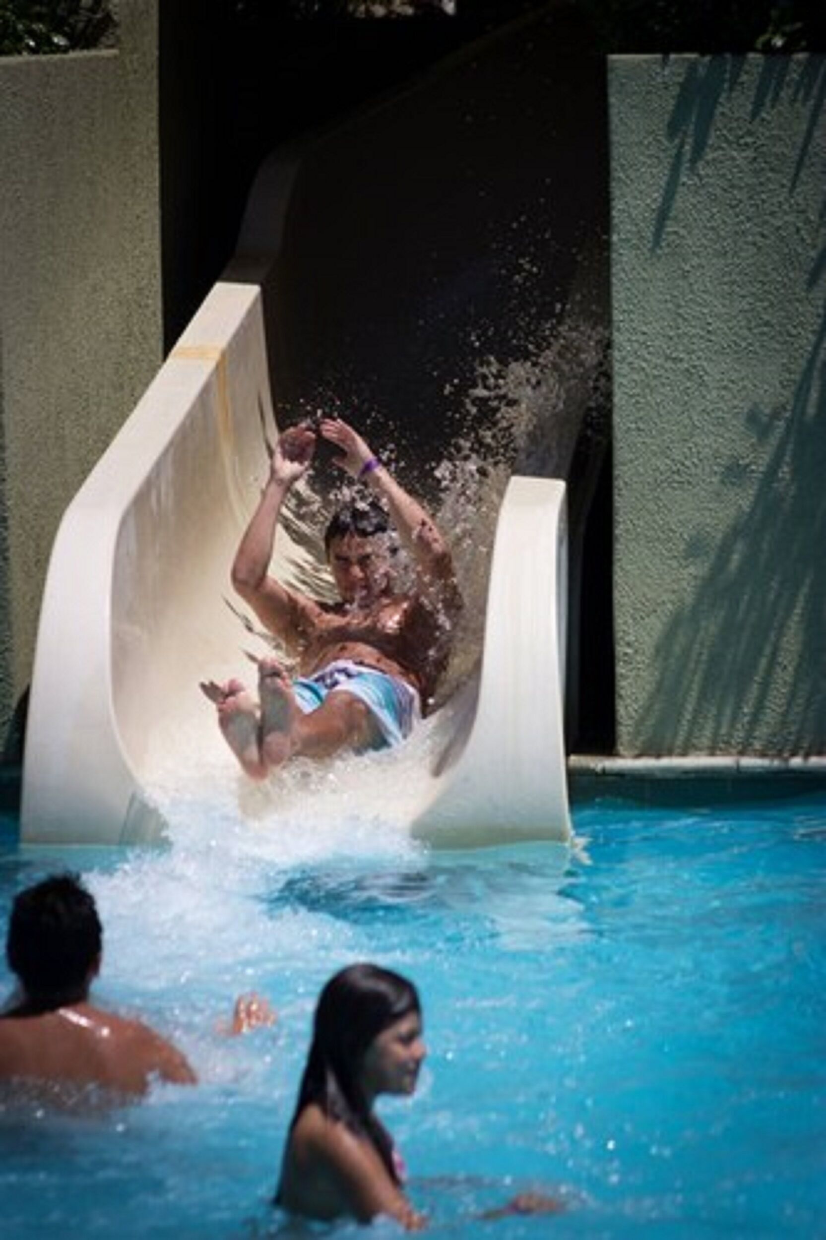 Tobogán de agua en una piscina con agua cristalina y una persona deslizándose.
