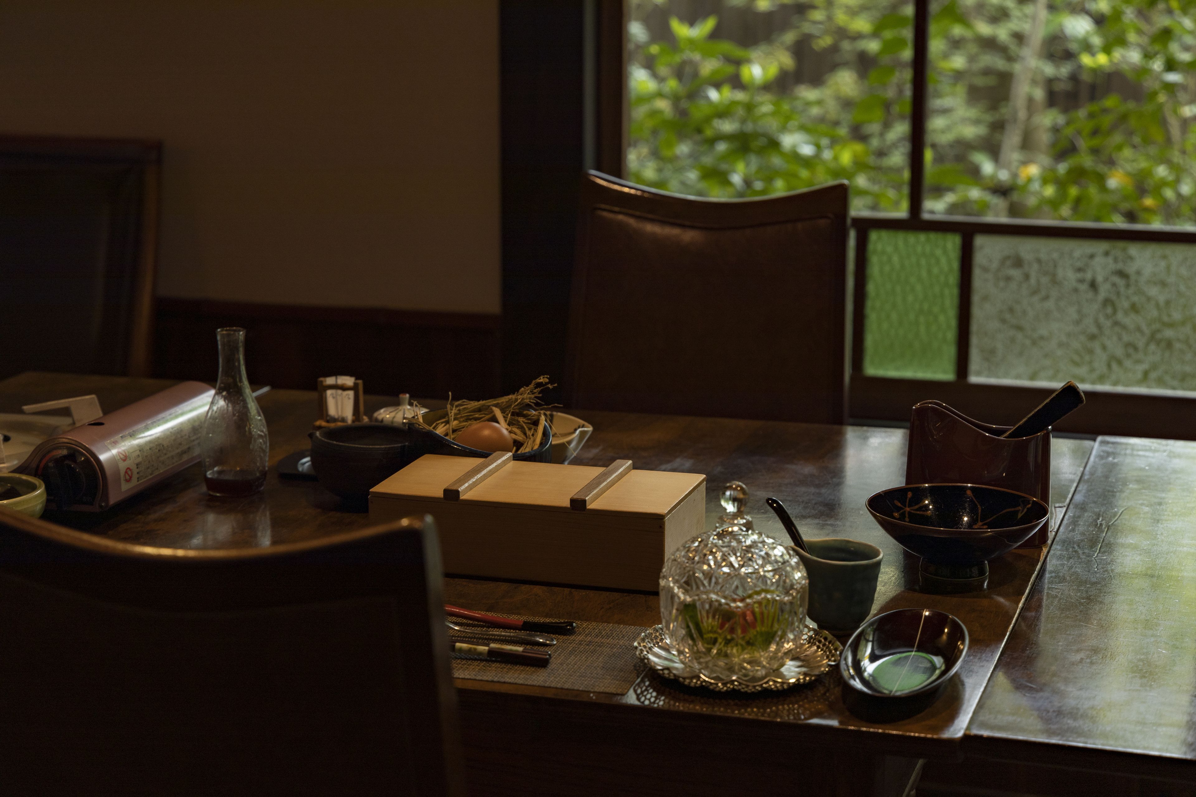A dining table with various items including a glass bottle, a box, a bowl, and a pitcher.
