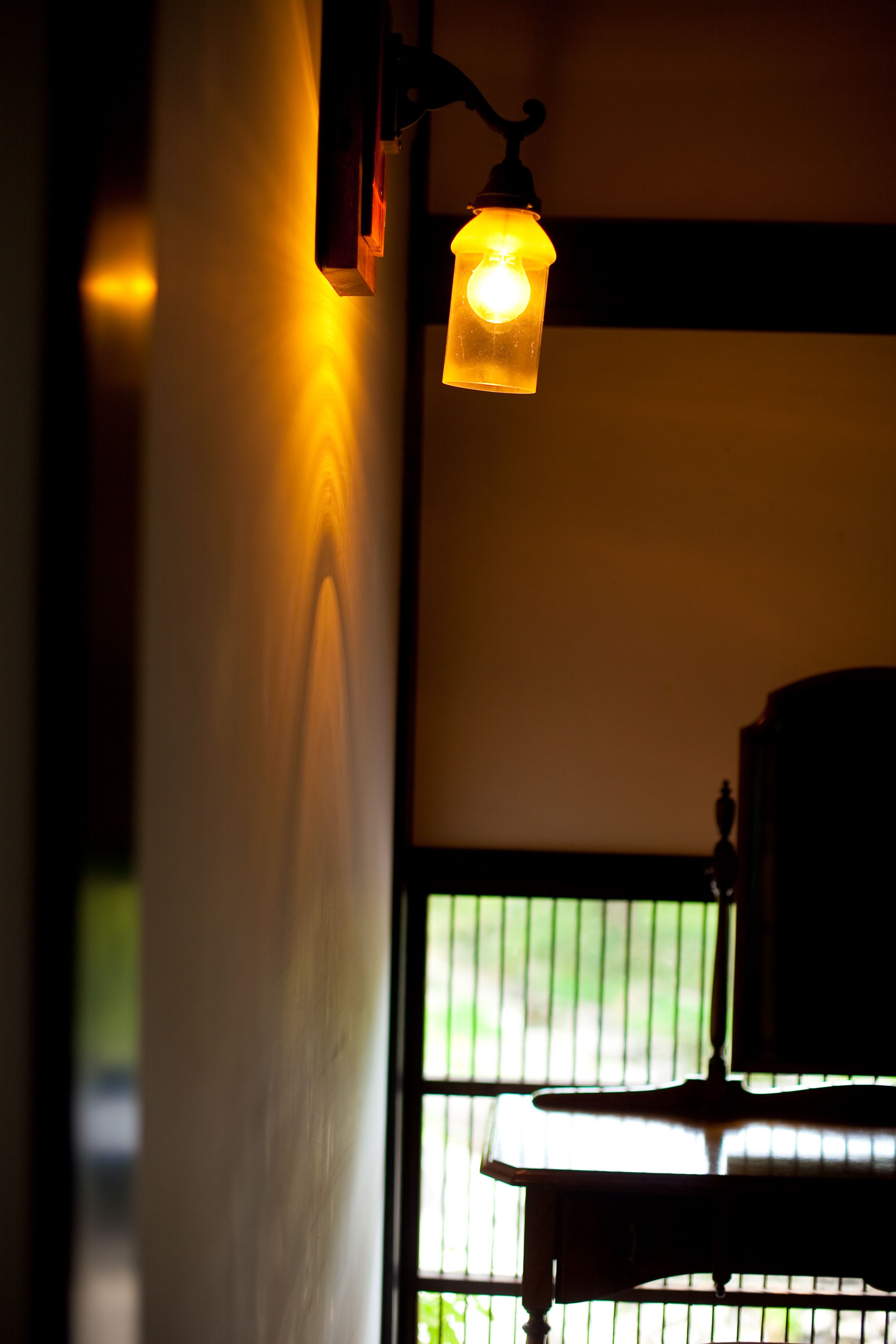 A room with a hanging light fixture and a window with a view of greenery outside.