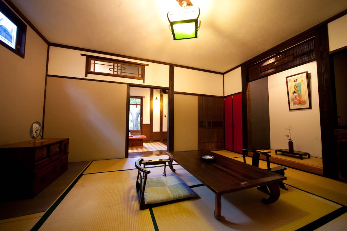 A traditional Japanese room with tatami flooring, a low wooden table, and a sliding door.