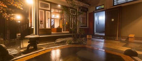 A traditional Japanese-style building with a wooden deck, a small pond, and a stone lantern.