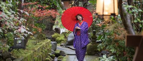 Un jardin japonais traditionnel avec un sentier de pierres, des rochers recouverts de mousse et une lanterne.