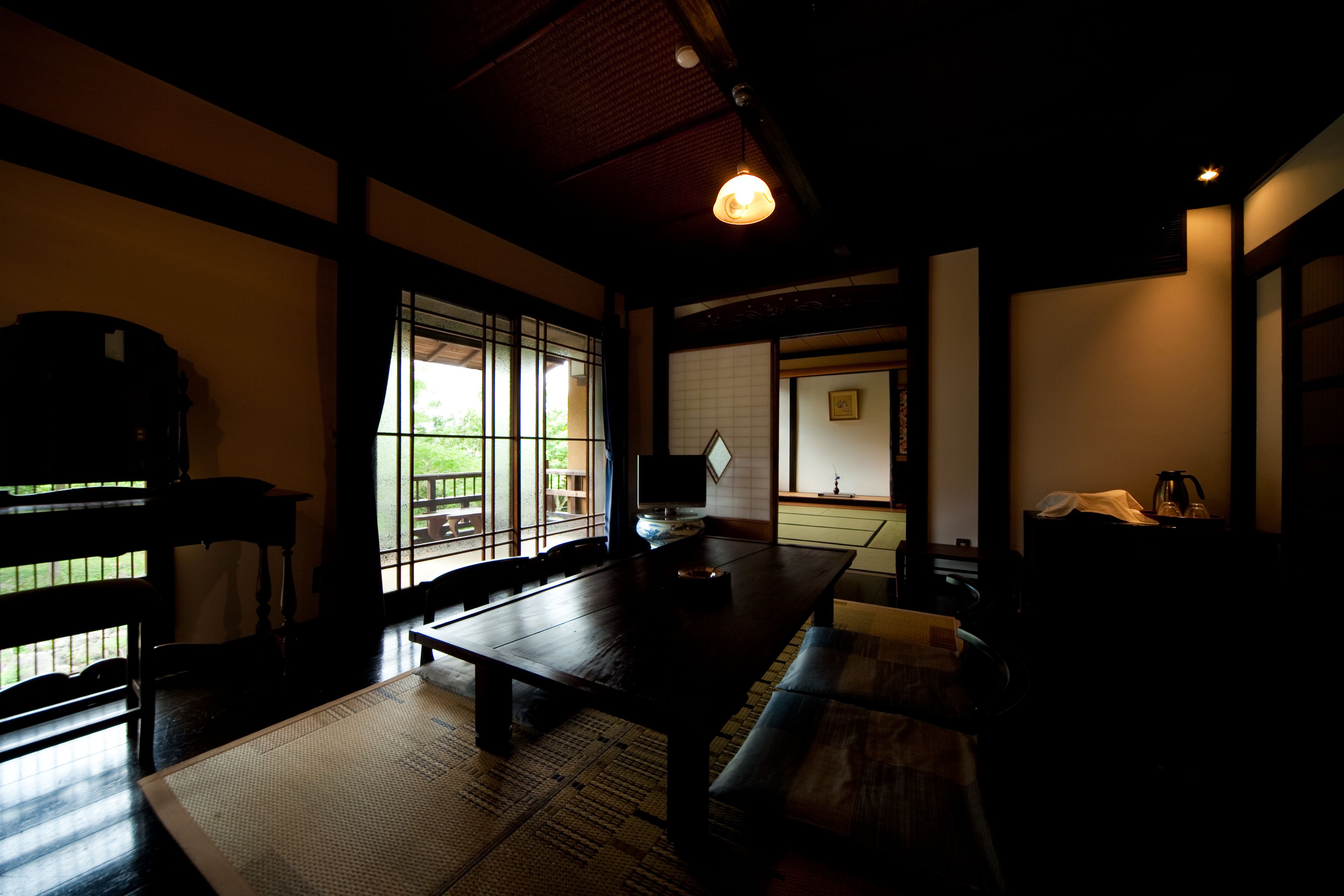 A traditional Japanese room with tatami flooring, a low table, and sliding doors.