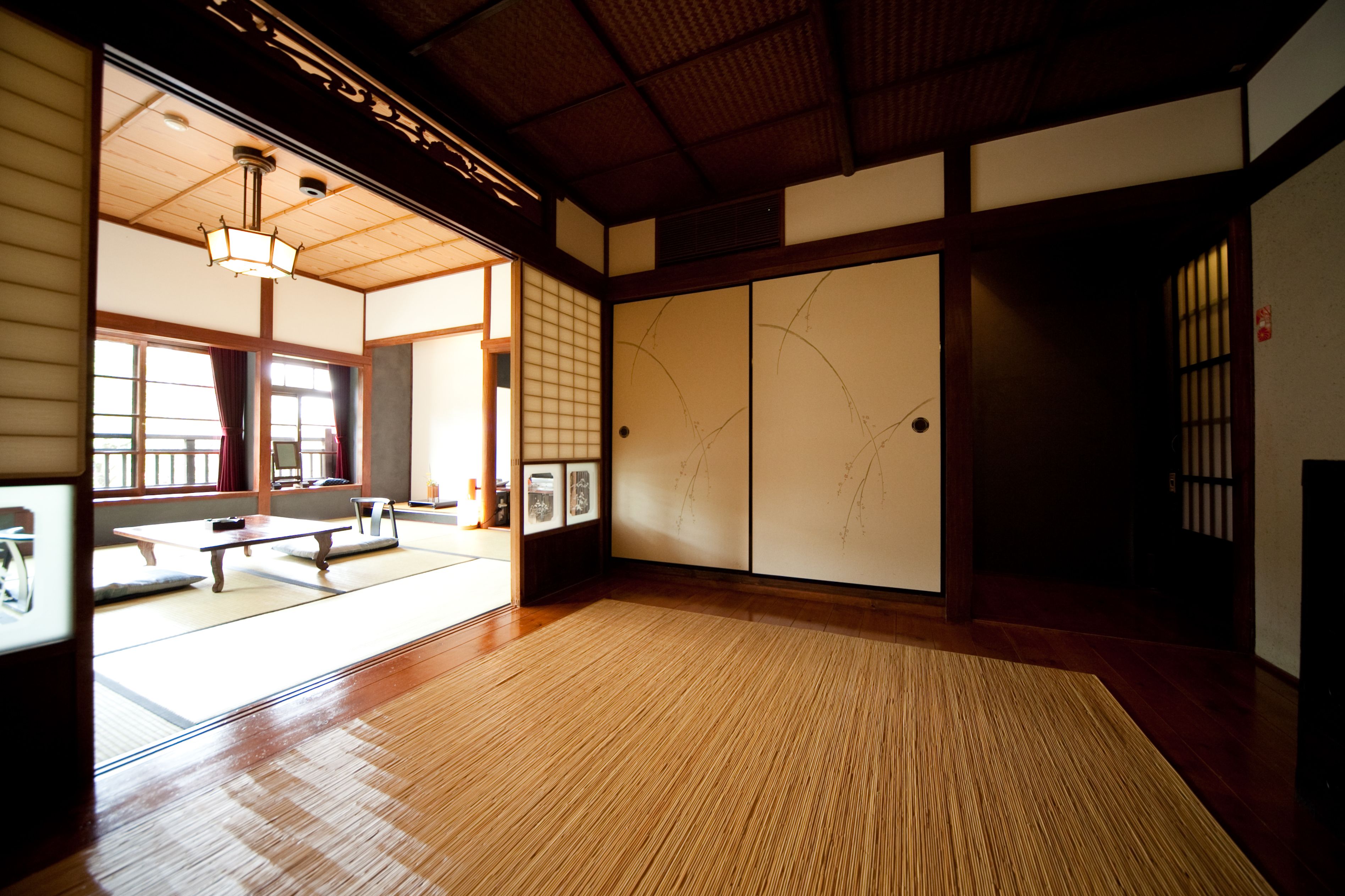 A traditional Japanese room with tatami flooring, sliding doors, and a low ceiling.