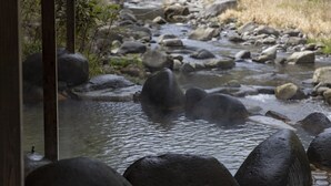 A river with large rocks and a wooden structure in the foreground.