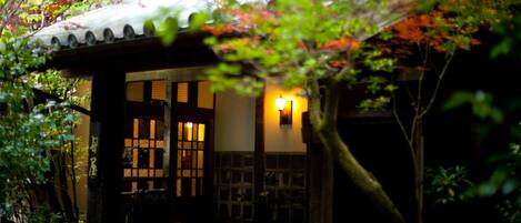 A traditional Japanese-style building with a tiled roof, wooden pillars, and a stone pathway leading to the entrance.