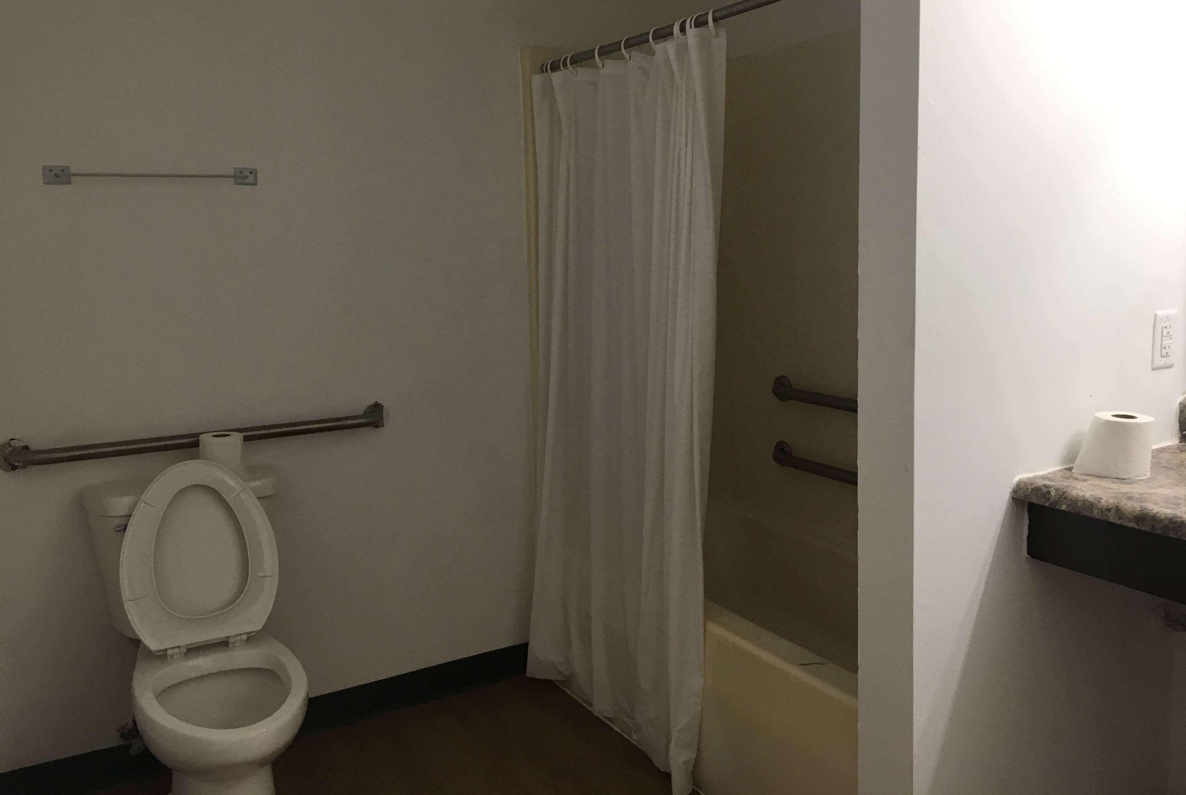 Une salle de bain équipée de toilettes, d’un rideau de douche et d’un porte-serviettes.