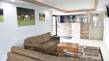 A living room with a sofa, a coffee table, and a fireplace. There is a door leading to a balcony with a view of trees.