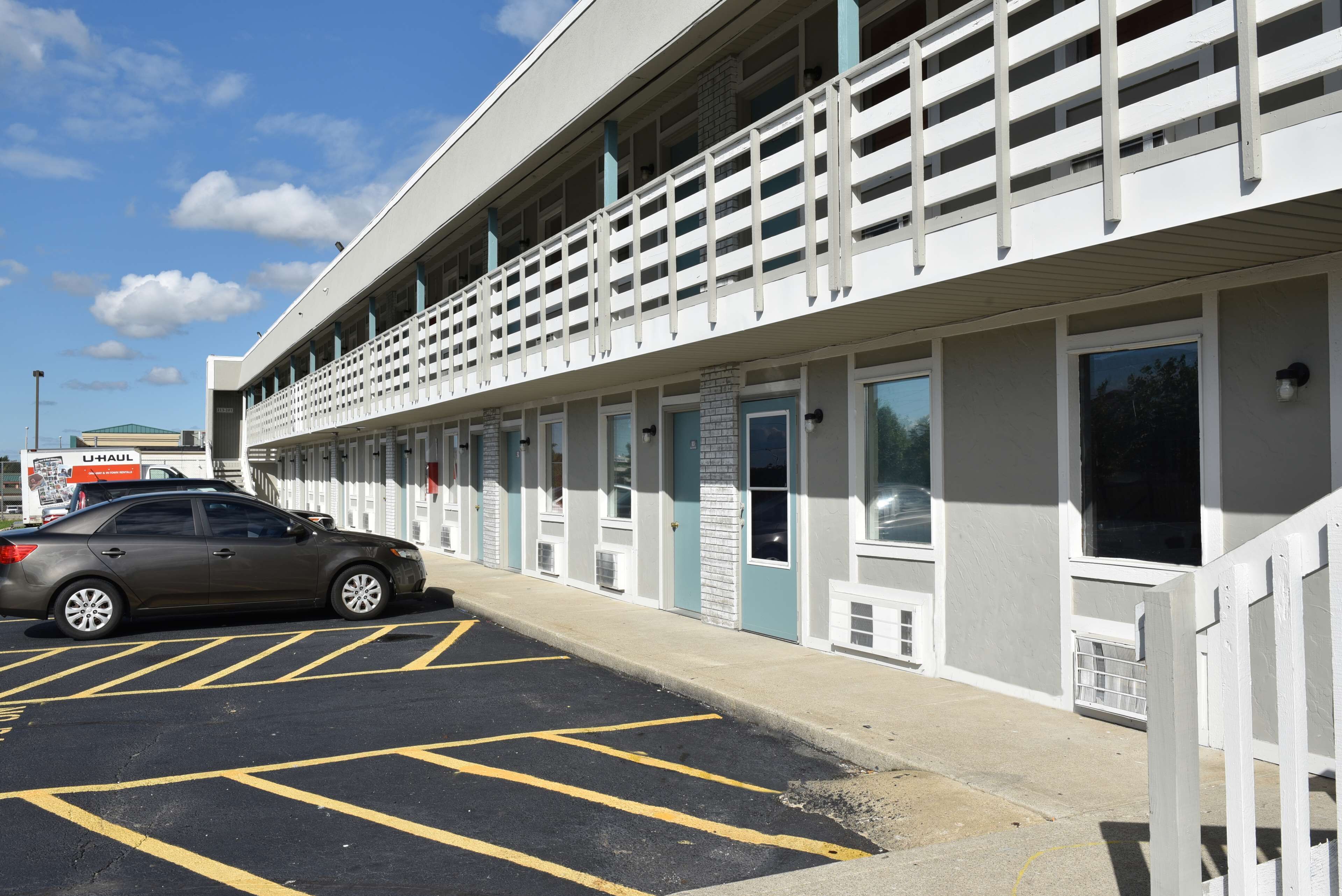 A hotel with a parking lot and a car parked in front.