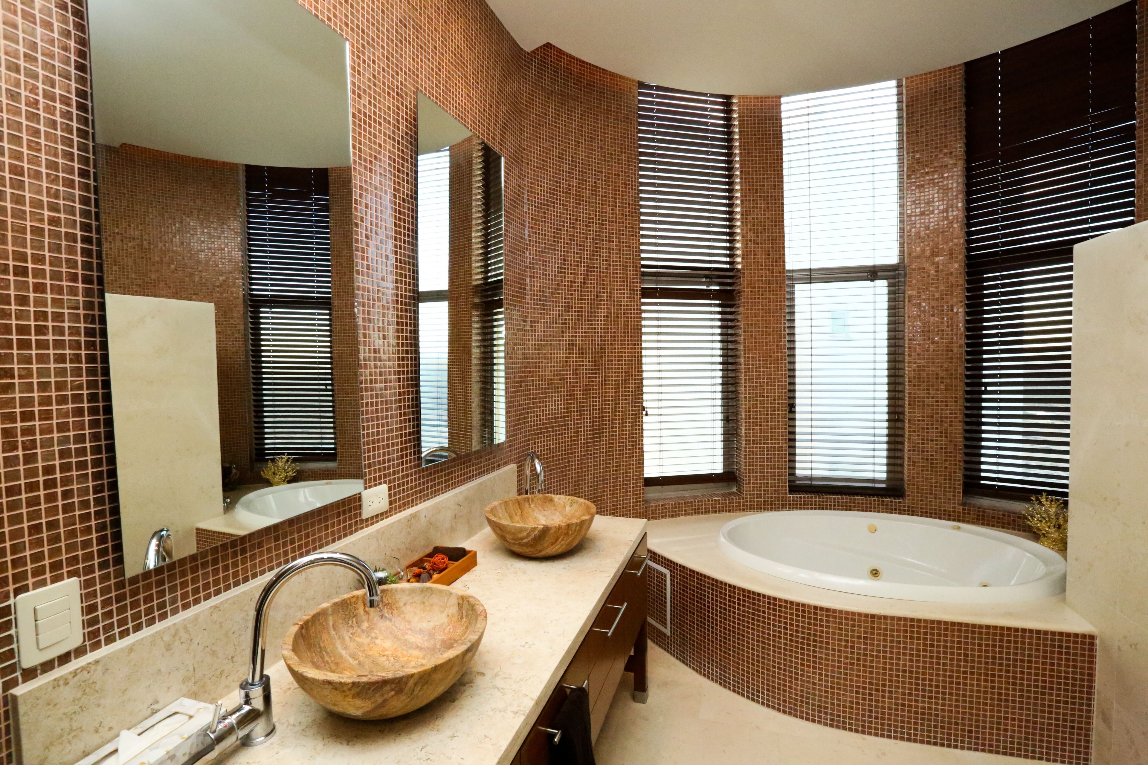 Un baño moderno con una bañera grande, dos cuencos de madera sobre el lavamanos y un espejo amplio.
