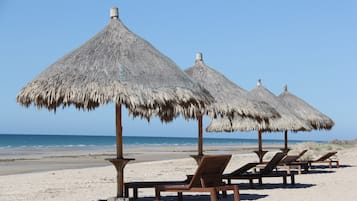 On the beach, white sand, sun loungers, beach umbrellas