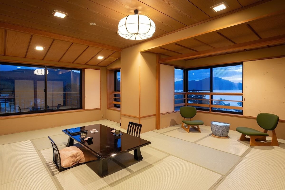 Une pièce de style japonais traditionnel, avec un sol recouvert de tatamis, une table basse et des chaises vertes.