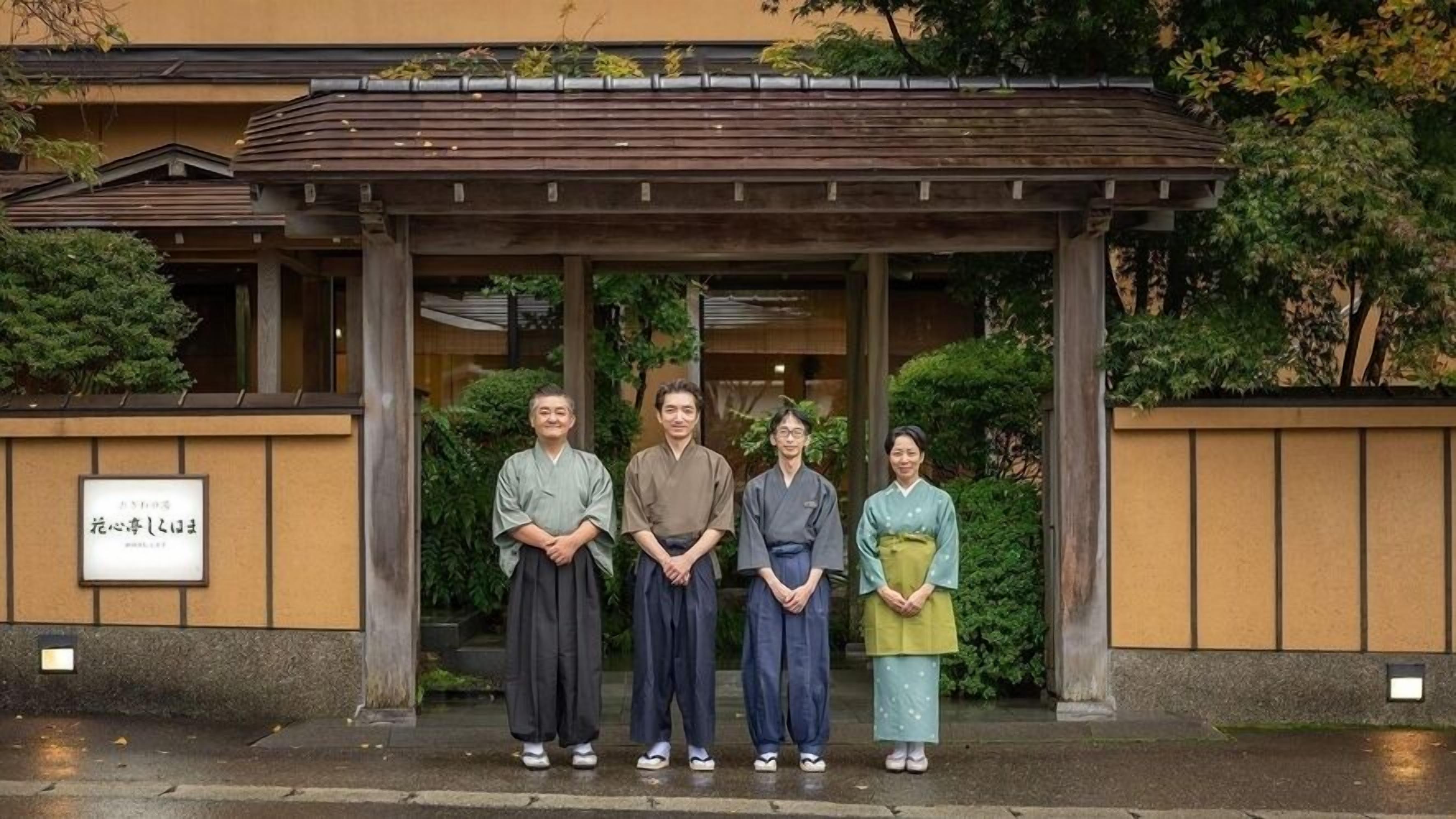Een traditioneel Japans gebouw met een overdekte ingang, een bord en een goed onderhouden tuin.