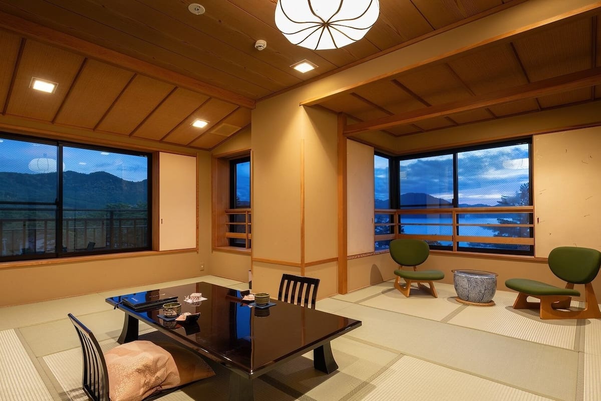 Une pièce de style japonais traditionnel, avec un sol recouvert de tatamis, une table basse et des chaises vertes.