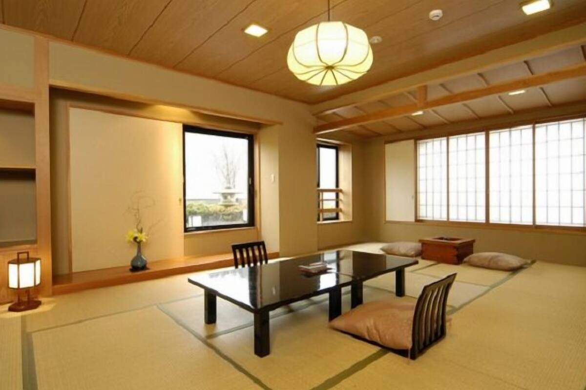 Une pièce de style japonais traditionnel, avec un sol recouvert de tatamis, une table basse et des portes coulissantes.