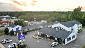 Un motel con un letrero grande, un estacionamiento y vistas a un área boscosa.