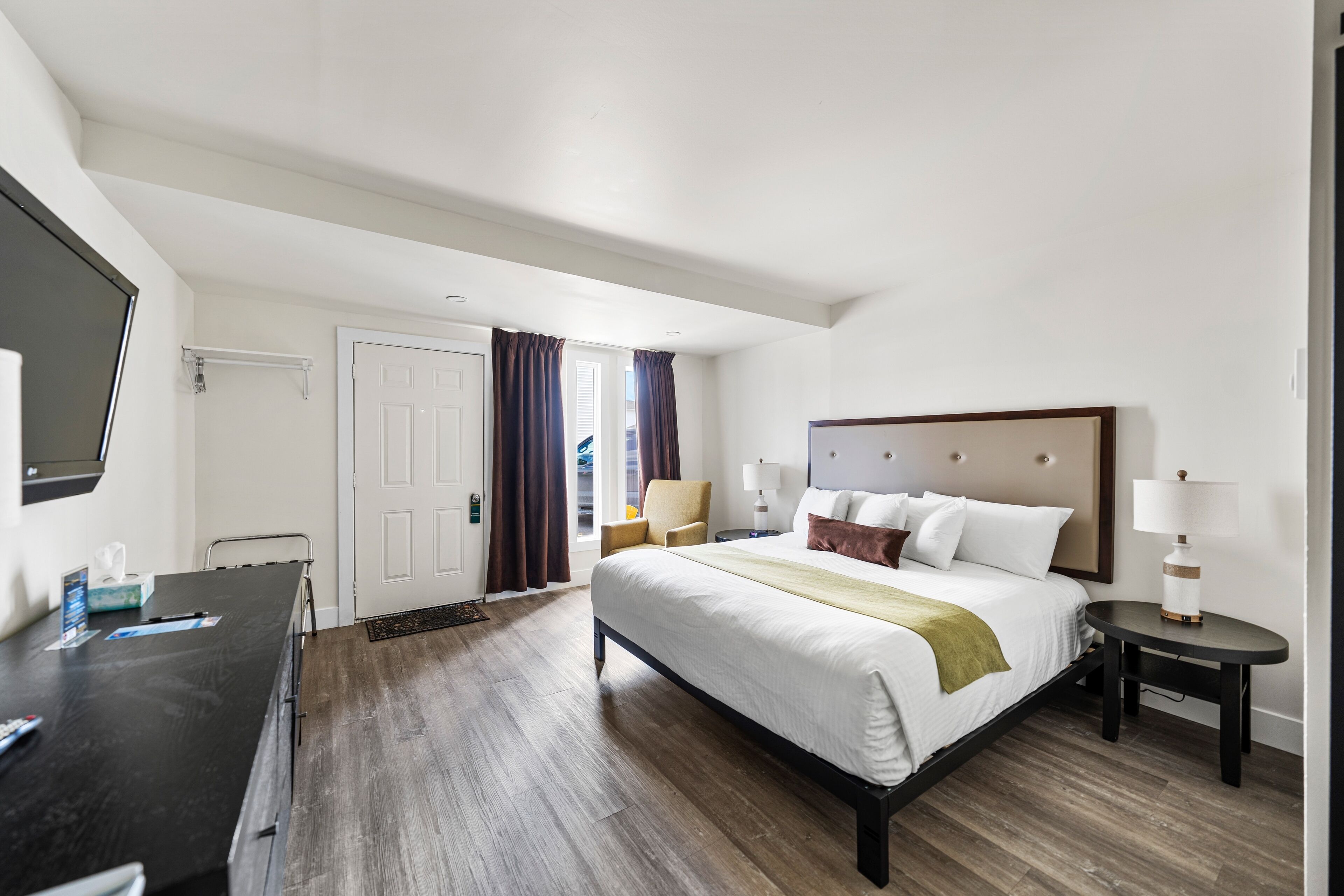 Quarto de hotel com uma cama grande, uma escrivaninha, uma cadeira e uma televisão.