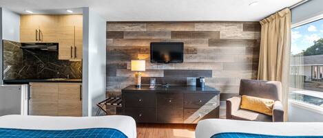 Una habitación de hotel moderna con una pared de madera, un televisor de pantalla plana, un escritorio con lámpara y dos camas con ropa de cama azul.