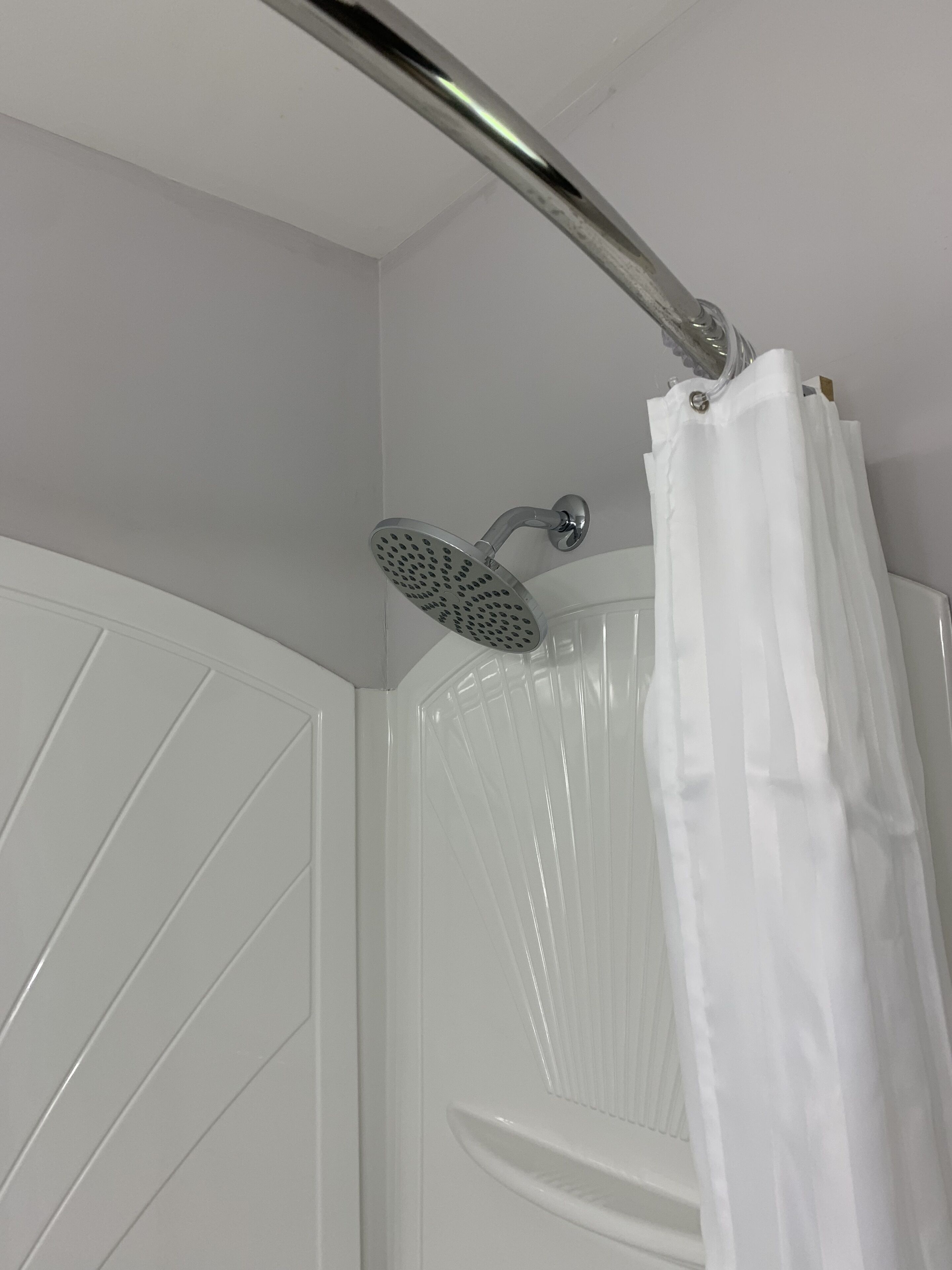 Ducha con grifo cromado y cortina blanca.
