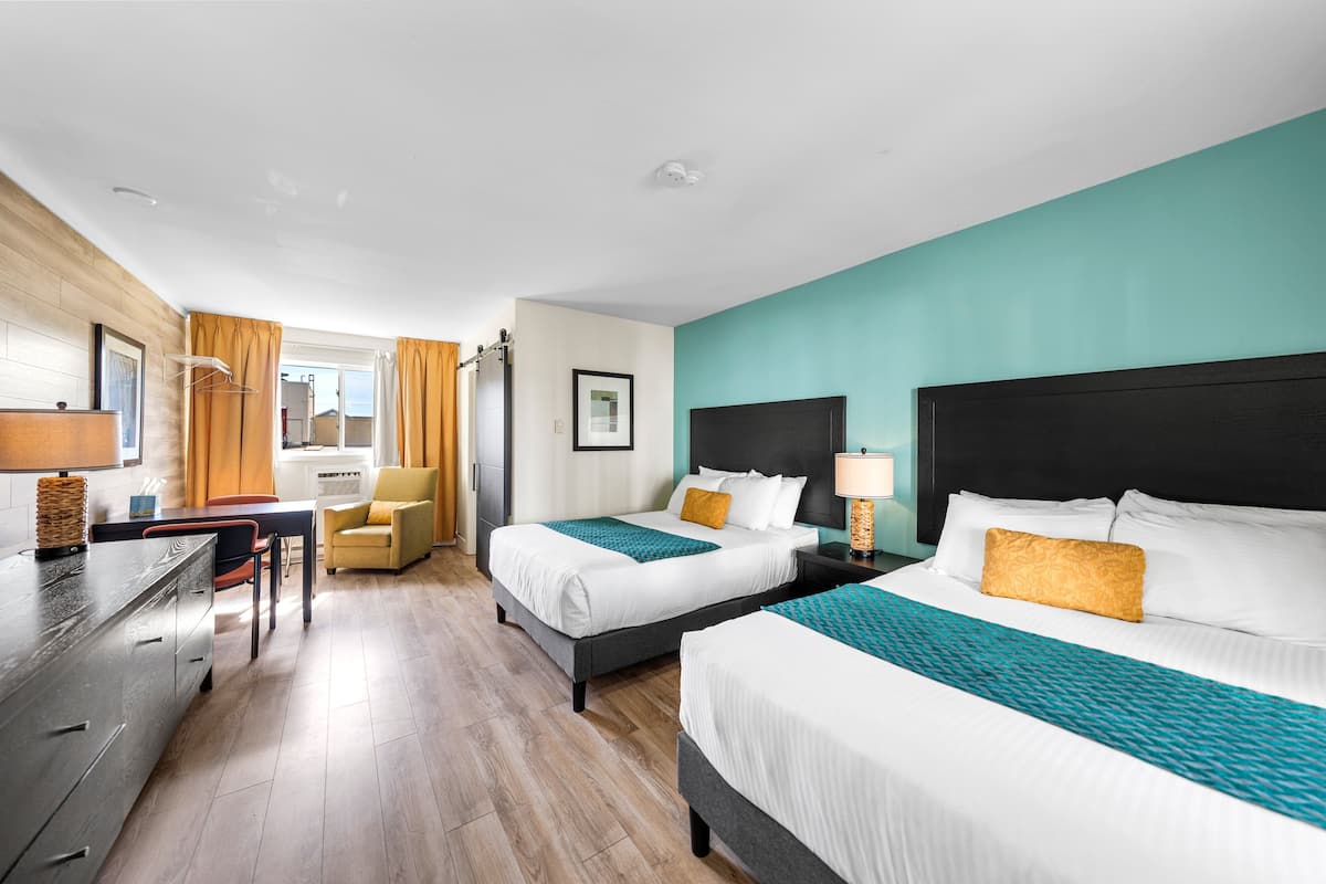 Ein Hotelzimmer mit zwei Betten, einem Schreibtisch, einem Stuhl und Blick ins Freie.