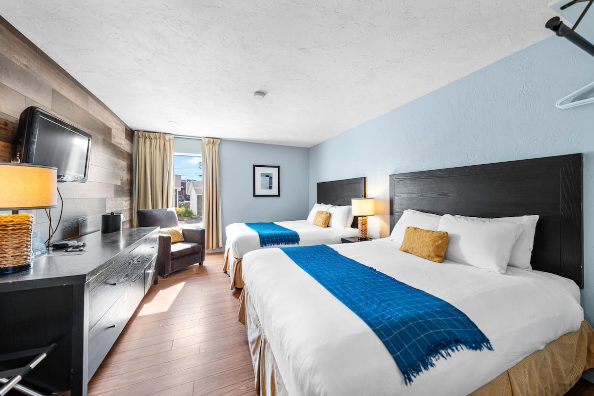 Ein Hotelzimmer mit zwei Betten, einem Schreibtisch mit Fernseher und Blick ins Freie.