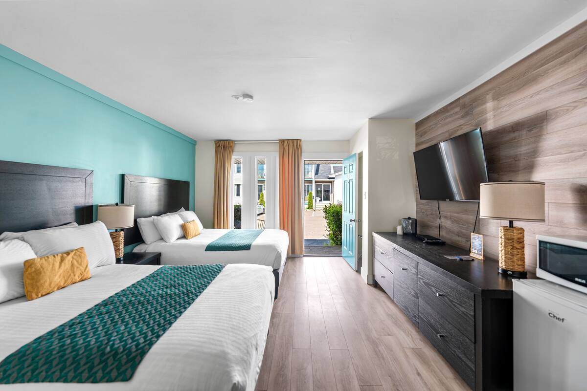 Ein Hotelzimmer mit zwei Betten, einem Fernseher, einer Minibar und Blick ins Freie.