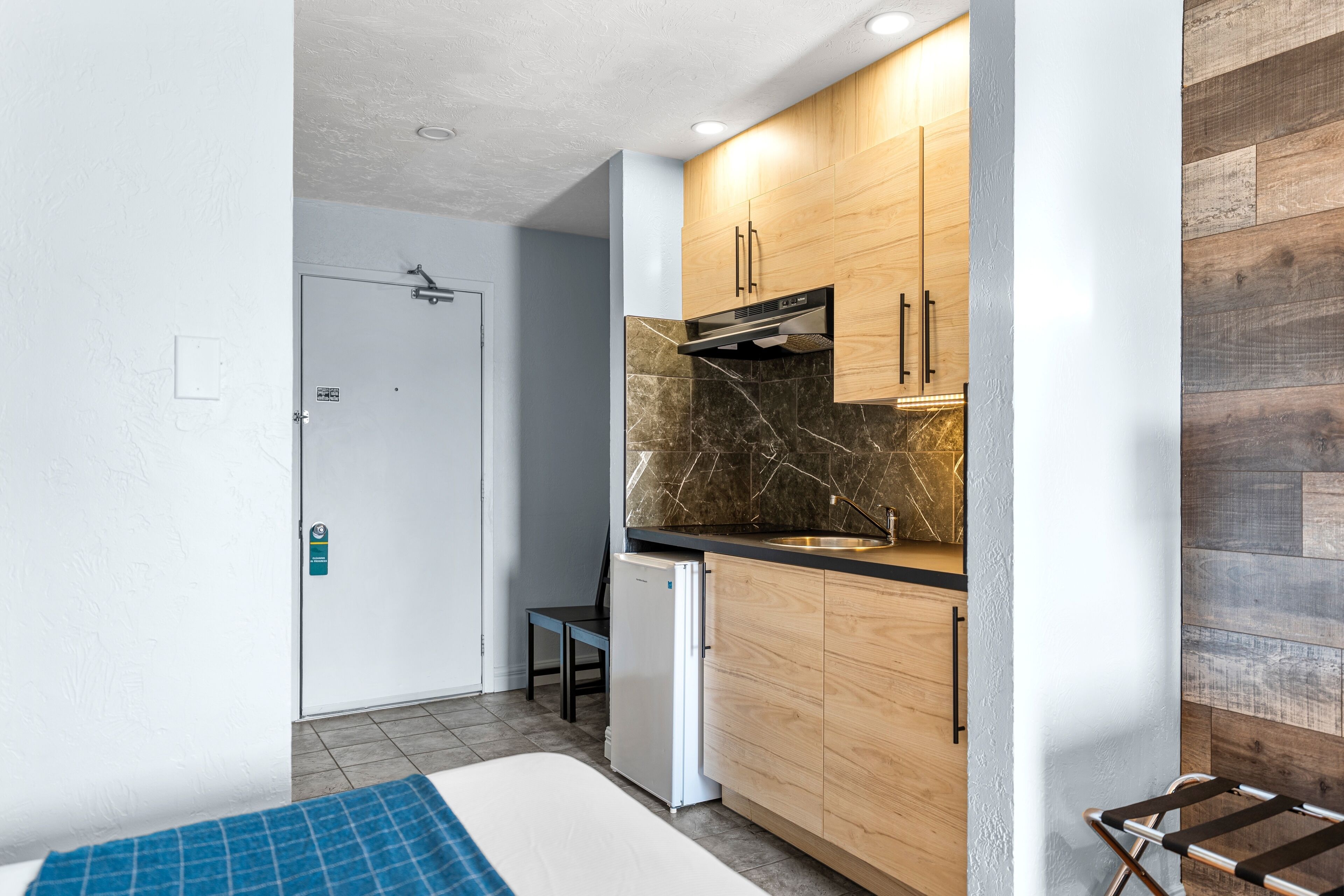 Una cocina compacta con armarios de madera, horno empotrado y un refrigerador pequeño.