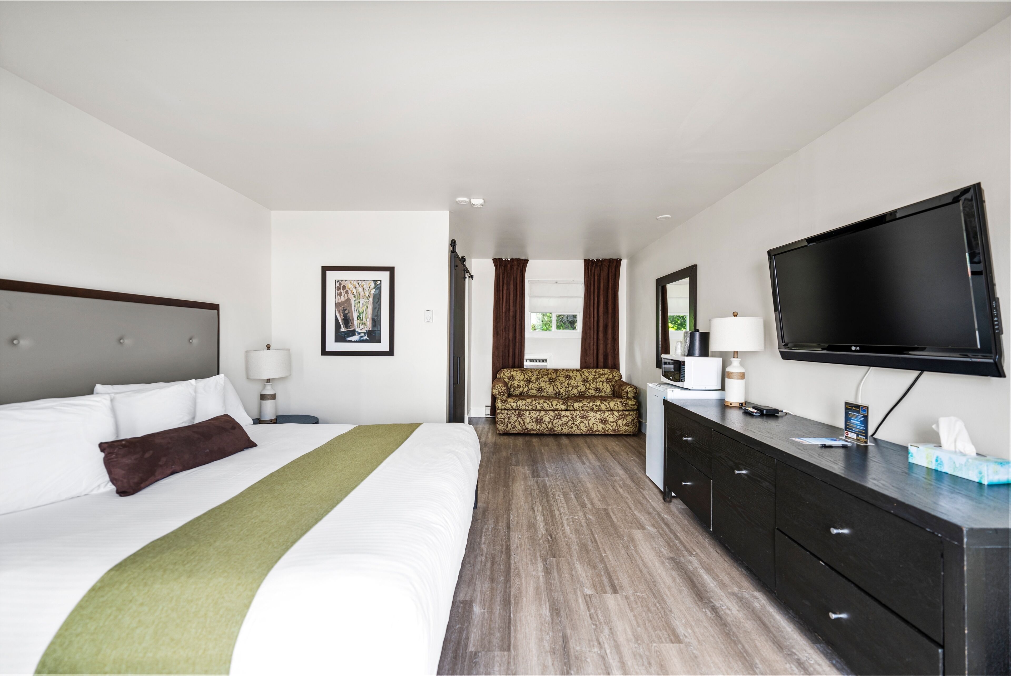 Une chambre d’hôtel avec un grand lit, un canapé, une télévision et un bureau.