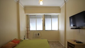 Ein Schlafzimmer mit einem Bett, einem Fernseher und einem Fenster mit Jalousien.