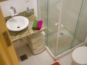 A bathroom with a sink, a glass shower enclosure, and a toilet.