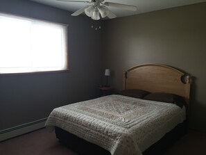 A bedroom with a bed, a ceiling fan, a nightstand, and a window with blinds. - Northwinds Motel (Northern Bruce Peninsula)