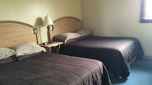 Two beds with dark bedding, a bedside table with a lamp, and a wooden headboard. - Northwinds Motel (Northern Bruce Peninsula)
