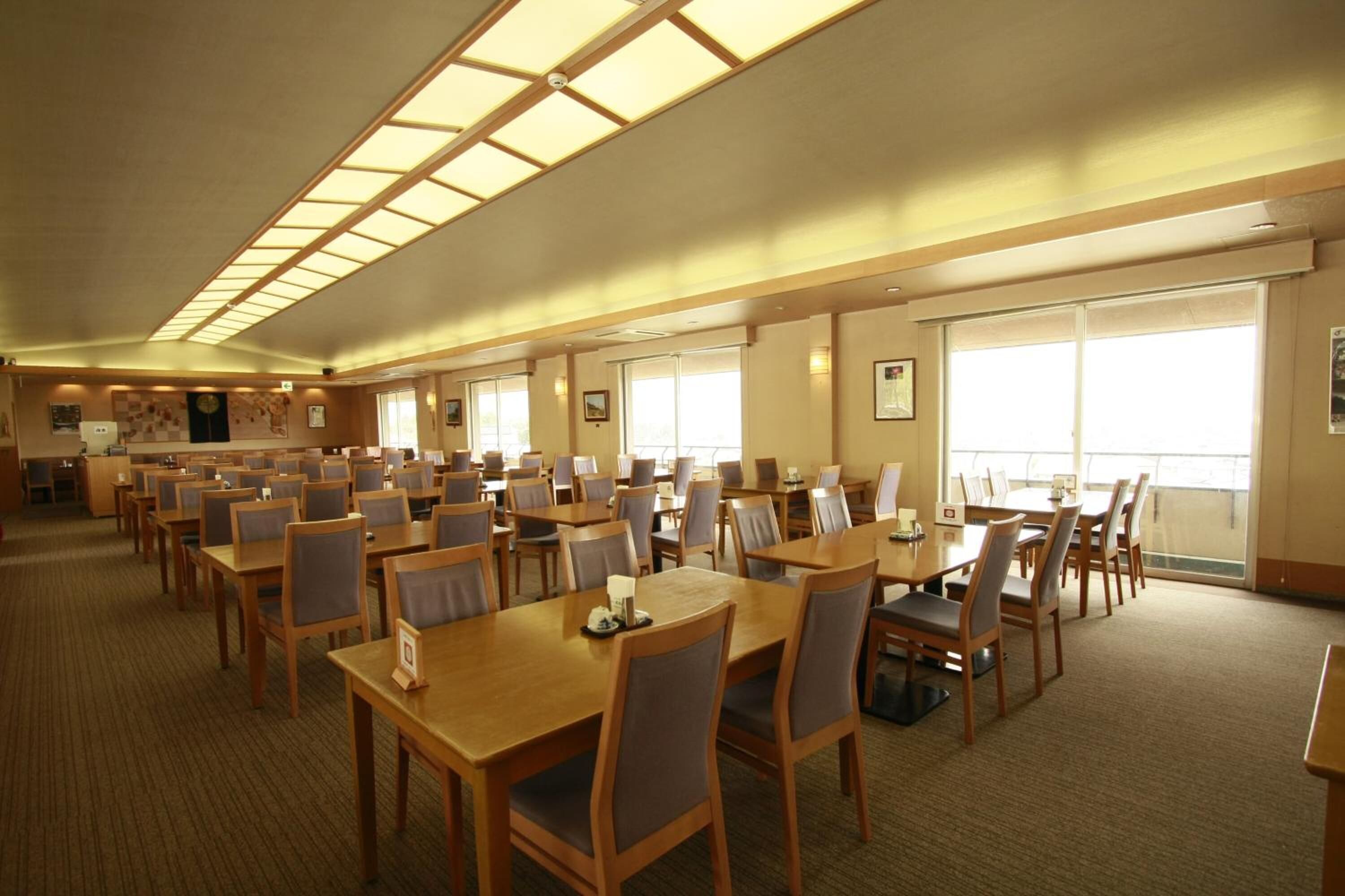 A large conference room with multiple tables and chairs, high ceilings with skylights, and large windows providing natural light.