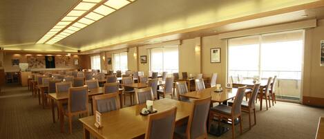 A large conference room with multiple tables and chairs, high ceilings with skylights, and large windows providing natural light.