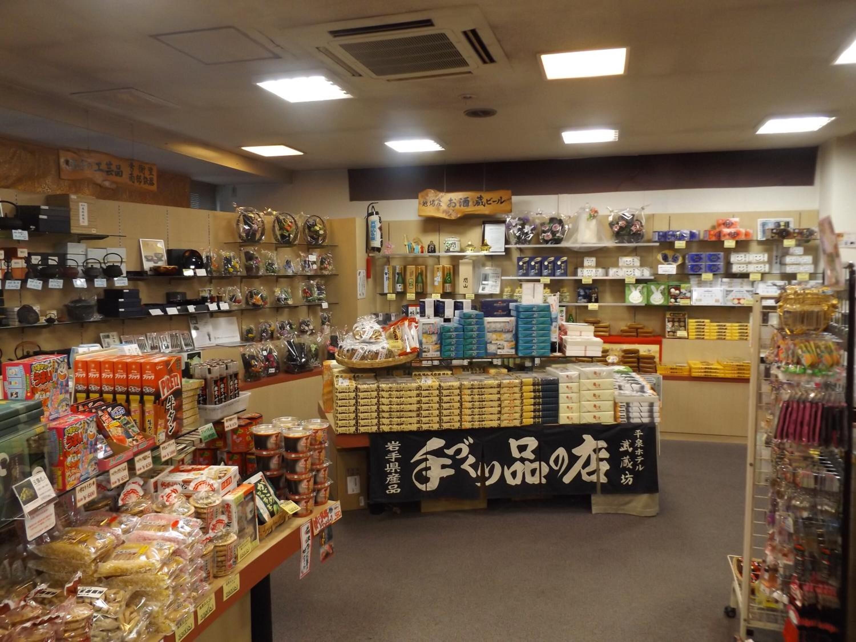 A store with shelves of packaged goods, a display table with boxed items, and a sign with Japanese text.