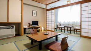 A traditional Japanese room with tatami flooring, a low table, chairs, a TV, and sliding doors. - Hiraizumi Hotel Musashibou (Hiraizumi)
