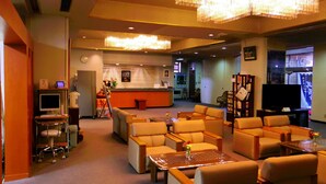 A hotel lobby with a reception desk, seating area, and a television. - Hiraizumi Hotel Musashibou (Hiraizumi)