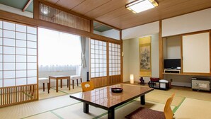 A traditional Japanese room with tatami flooring, a low table, chairs, a television, and a cabinet. - Hiraizumi Hotel Musashibou (Hiraizumi)
