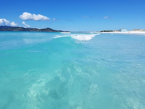 A beach with clear turquoise water, a sandy shore, and distant hills. - Terra Nova Cabo Frio Front Beach (Cabo Frio)