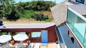 A pool area with a view of the ocean, outdoor seating, and a modern building with large windows. - Terra Nova Cabo Frio Front Beach (Cabo Frio)