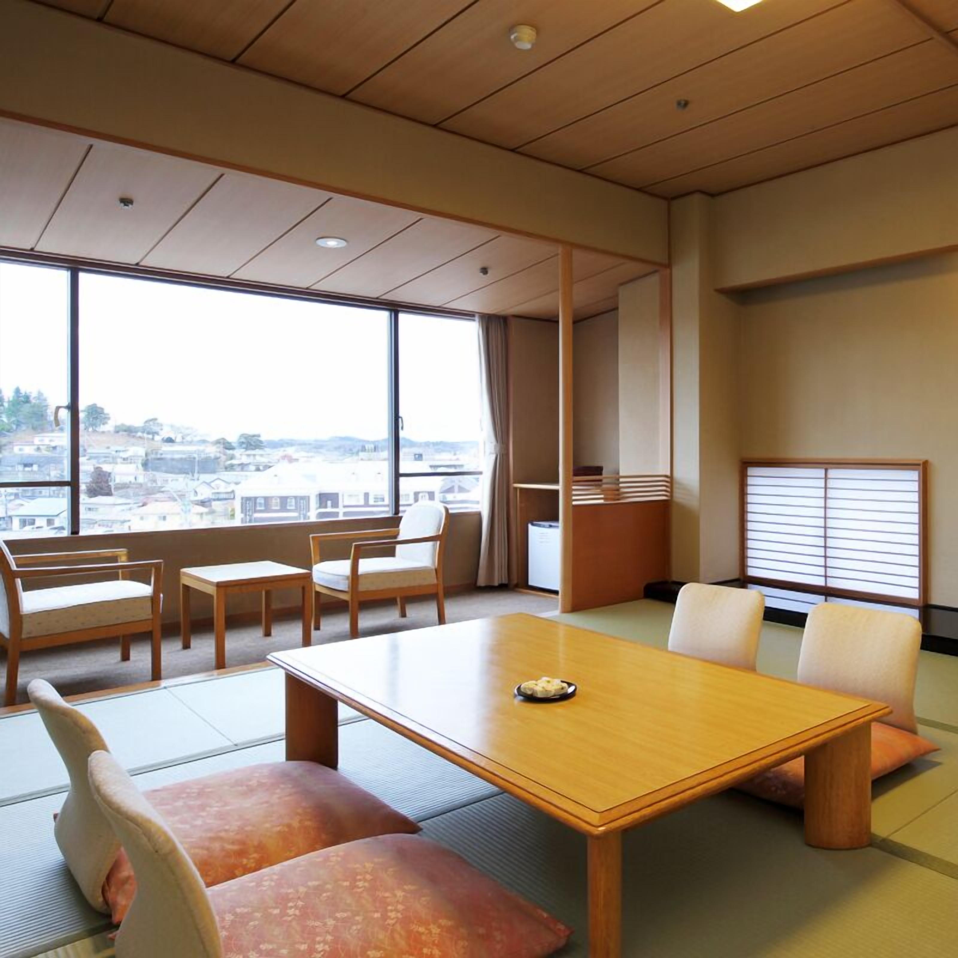 A room with a large window, a wooden table, and seating arrangements.
